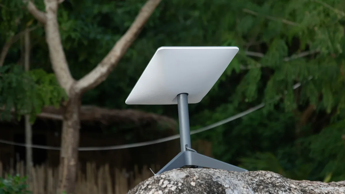 Antena Starlink na postolju na stijeni među drvećem